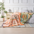 Cotton throw blanket styled on a bed with neutral linen pillows and natural wood headboard