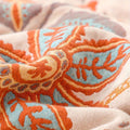 Lifestyle shot of the floral cotton blanket used as a cozy wrap in a reading nook